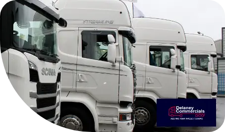 Row of new white semi-trucks for sale with the logo and branding of Delaney Commercials.